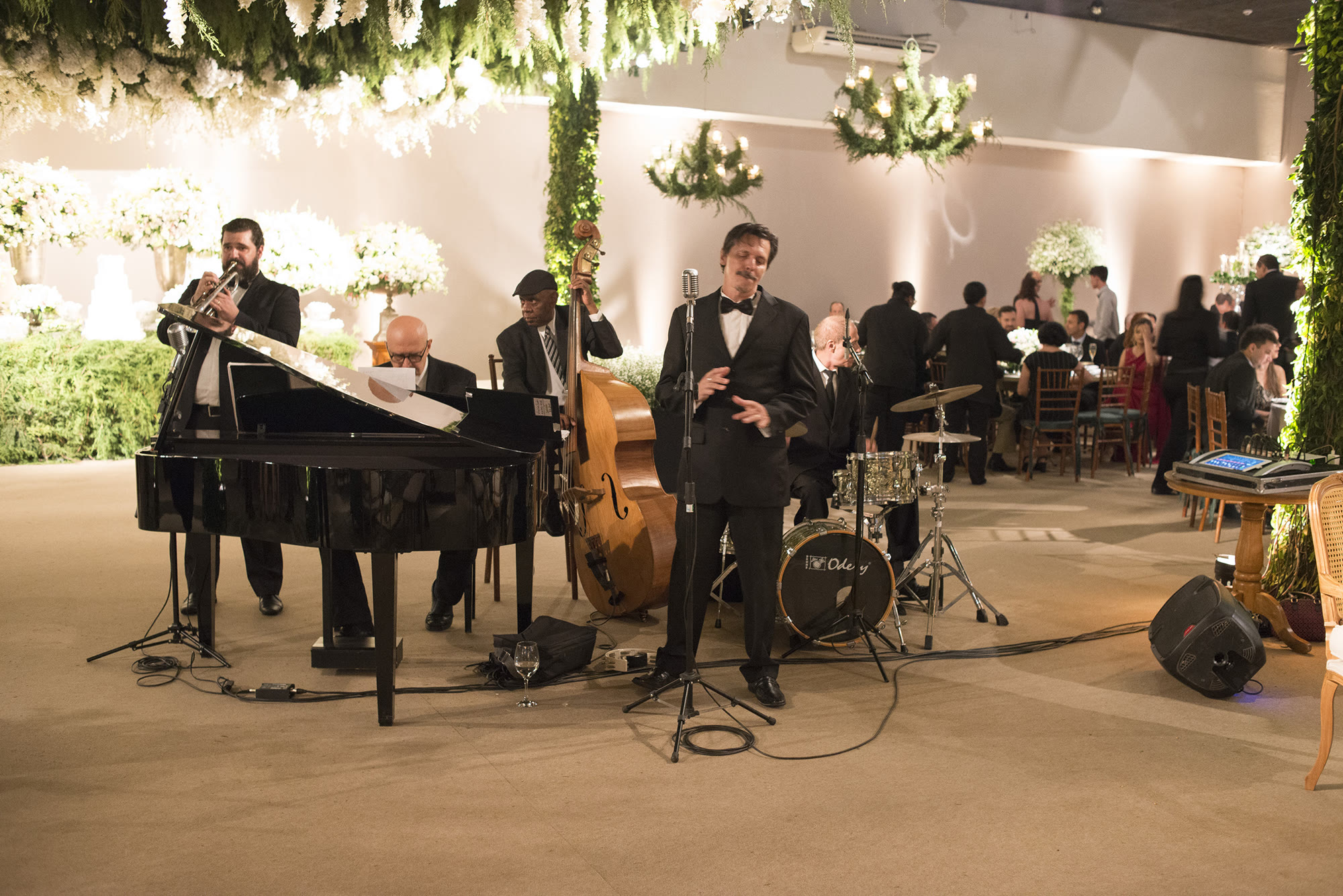 Jazz Maison com piano, contrabaixo, voz, metais e bateria em uma recepção
